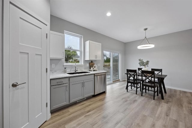 kitchen featuring gray cabinetry, a sink, light countertops, light wood-style floors, and stainless steel dishwasher