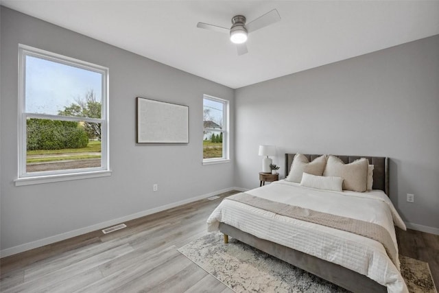 bedroom featuring wood finished floors, baseboards, visible vents, and ceiling fan