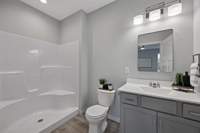 full bathroom with vanity, wood finished floors, baseboards, a shower, and toilet