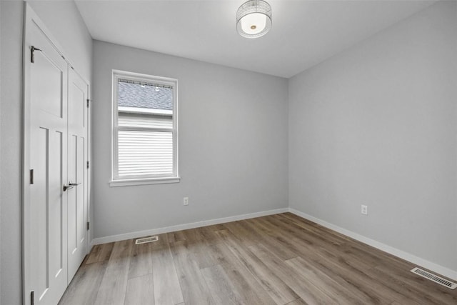 unfurnished bedroom featuring light wood-style floors, visible vents, a closet, and baseboards