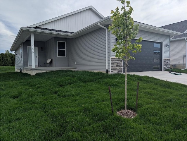 4177 Justified Dr, Marion, IA 52302 - view of front of house featuring concrete driveway, an attached garage, a front yard, board and batten siding, and covered porch