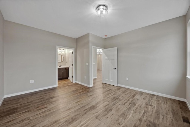 4193 Justified Dr, Marion, IA 52302 - unfurnished bedroom with wood finished floors, baseboards, and ensuite bath
