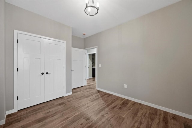4193 Justified Dr, Marion, IA 52302 - unfurnished bedroom featuring wood finished floors, baseboards, a closet, and a chandelier