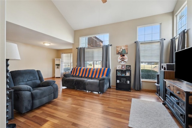 living area with high vaulted ceiling, a ceiling fan, and wood finished floors