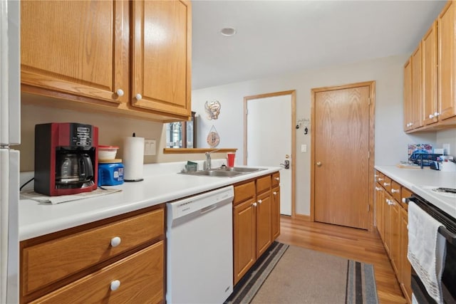 kitchen featuring light wood-style flooring, white appliances, light countertops, and a sink