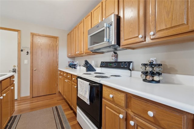 kitchen with light wood-type flooring, stainless steel microwave, electric range oven, and light countertops