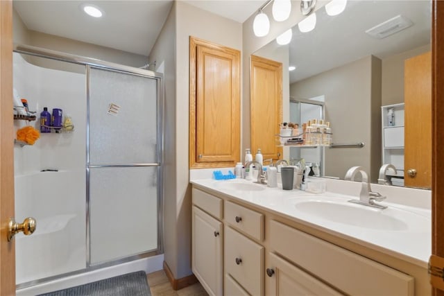 bathroom with double vanity, visible vents, a shower stall, and a sink