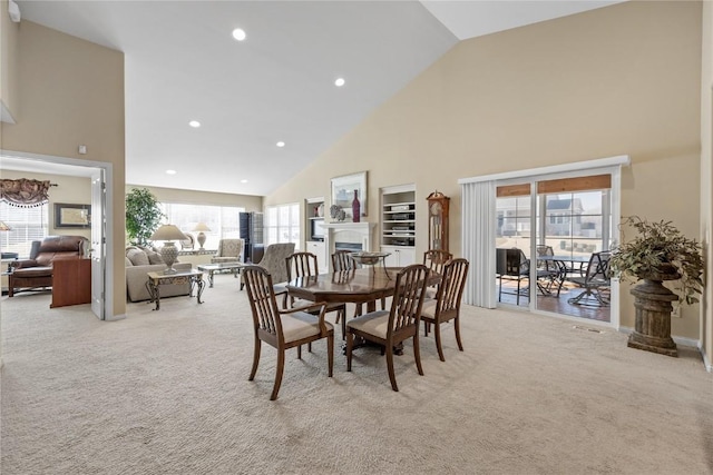 dining space featuring plenty of natural light, light colored carpet, and high vaulted ceiling