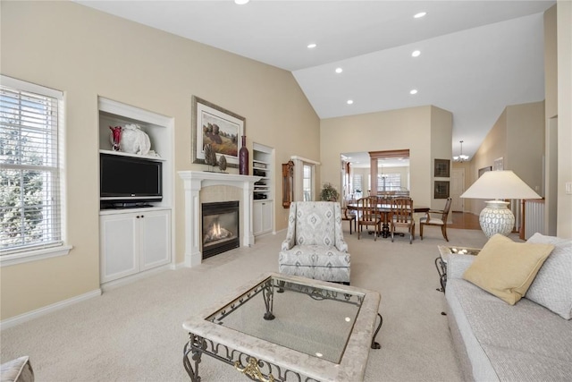 carpeted living area with built in shelves, baseboards, high vaulted ceiling, recessed lighting, and a glass covered fireplace