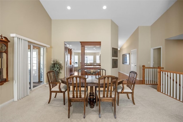 dining area featuring recessed lighting, baseboards, light carpet, and a towering ceiling