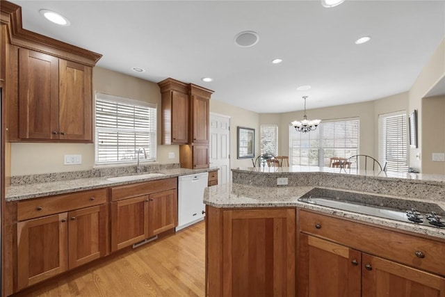 kitchen featuring a healthy amount of sunlight, a sink, electric cooktop, dishwasher, and a notable chandelier