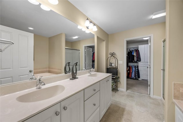 full bathroom featuring a garden tub, a spacious closet, a stall shower, and a sink