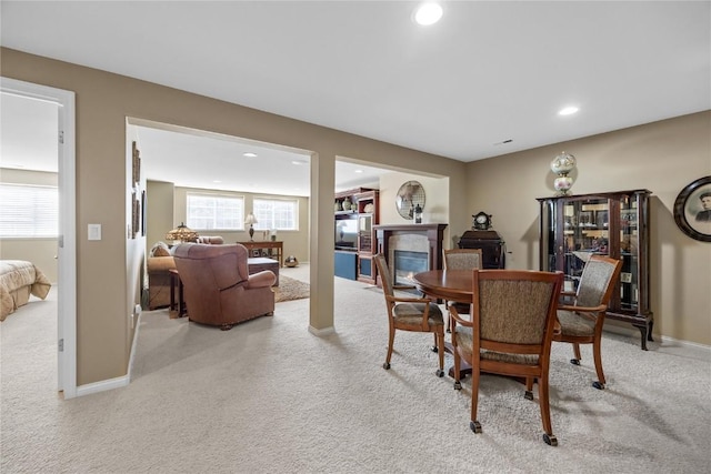 carpeted dining area with a glass covered fireplace, recessed lighting, a healthy amount of sunlight, and baseboards