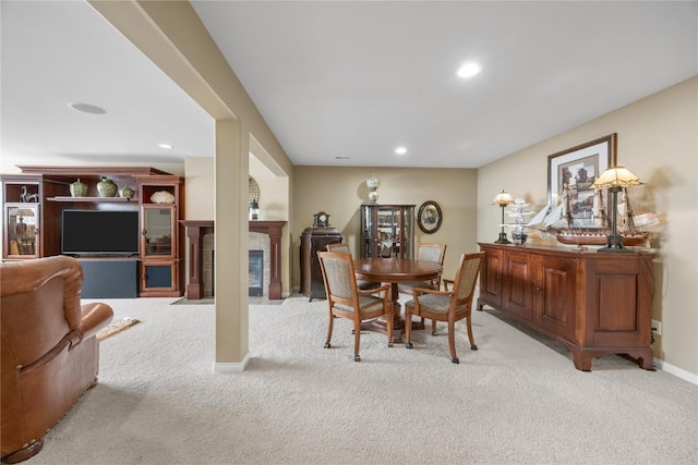 carpeted dining space featuring recessed lighting, a tile fireplace, and baseboards