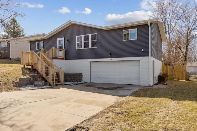 rear view of property featuring brick siding, fence, stairway, concrete driveway, and a garage