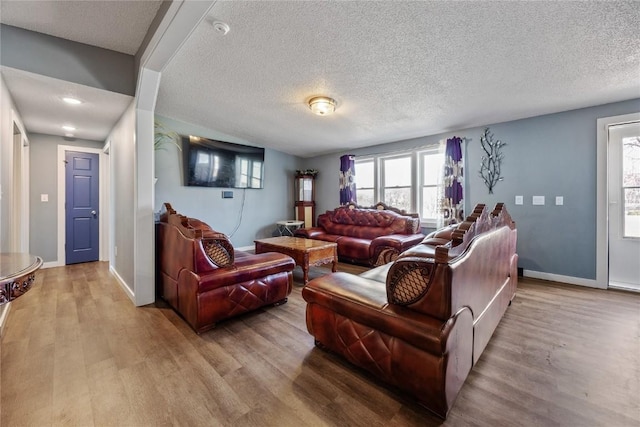 living room featuring a textured ceiling, baseboards, and wood finished floors