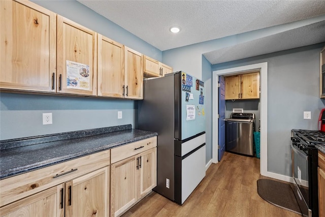 kitchen featuring black gas stove, light brown cabinets, freestanding refrigerator, and wood finished floors