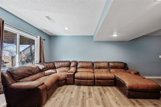 living area featuring light wood finished floors, visible vents, baseboards, recessed lighting, and a textured ceiling