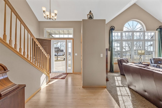 entryway with baseboards, stairs, wood finished floors, a notable chandelier, and high vaulted ceiling