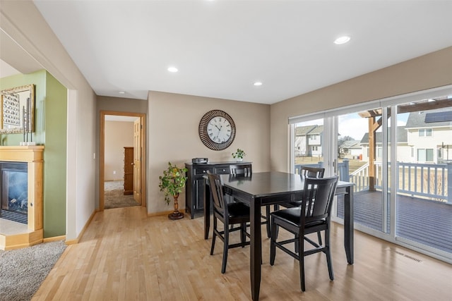 dining space featuring baseboards, visible vents, light wood-style flooring, recessed lighting, and a glass covered fireplace