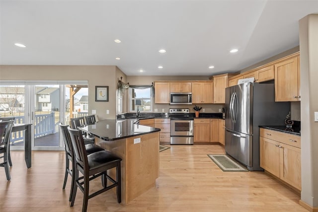 kitchen featuring light brown cabinetry, a peninsula, stainless steel appliances, and light wood-type flooring