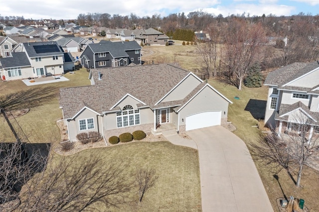 view of front of property featuring a residential view, concrete driveway, and an attached garage