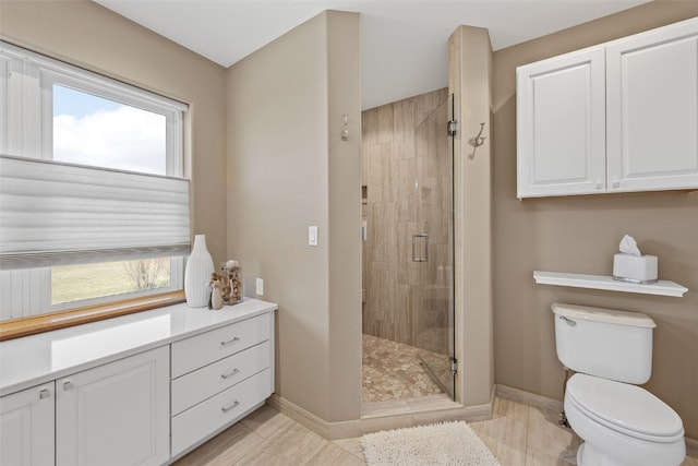 bathroom featuring a shower stall, toilet, and baseboards