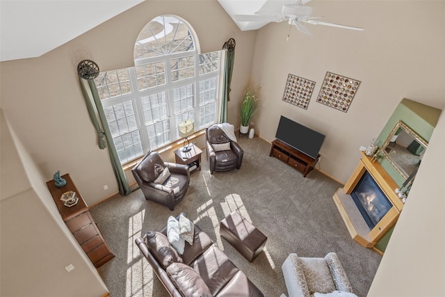 living area with a glass covered fireplace, high vaulted ceiling, carpet, and ceiling fan