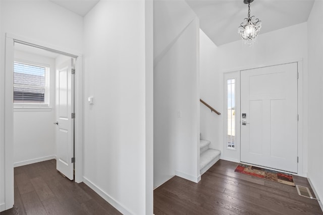 entrance foyer with stairway, dark wood-style floors, baseboards, and a chandelier