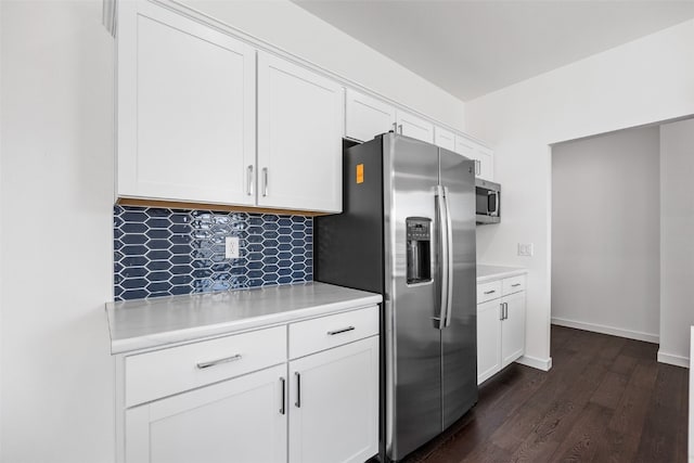 kitchen with dark wood-type flooring, appliances with stainless steel finishes, white cabinets, light countertops, and baseboards