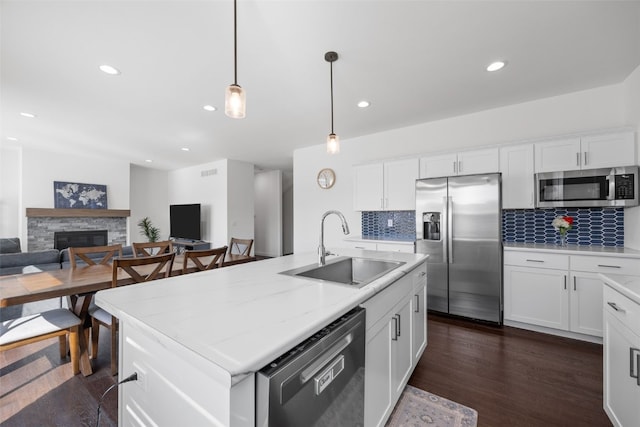 kitchen featuring a sink, stainless steel appliances, dark wood-style flooring, and a fireplace