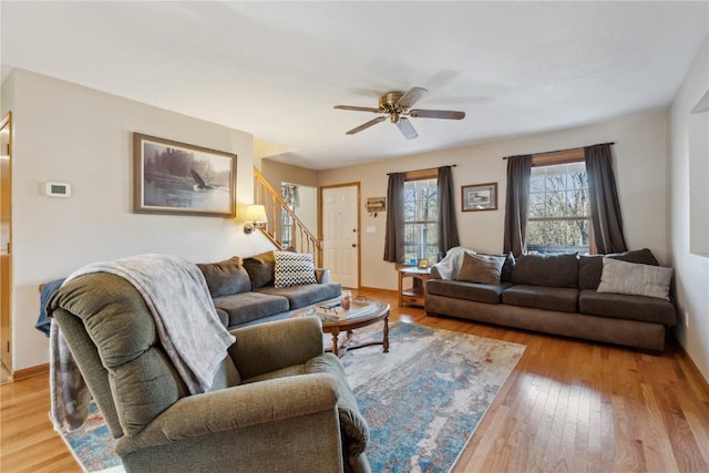 living area featuring stairs, light wood-style flooring, and ceiling fan