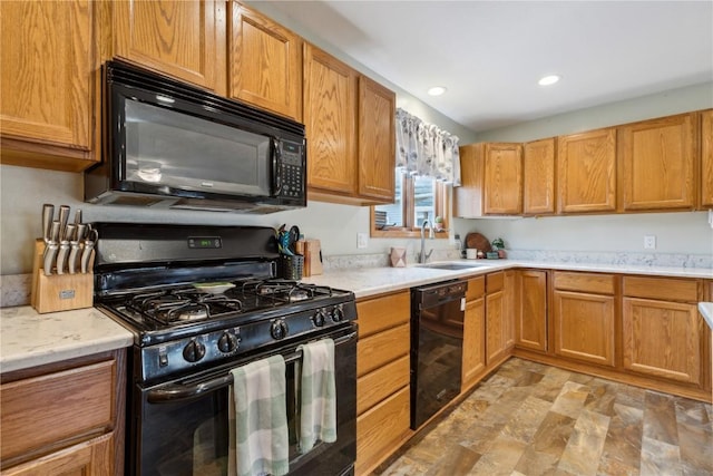 kitchen featuring light countertops, recessed lighting, stone finish floor, black appliances, and a sink