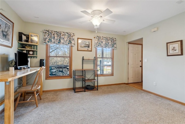 carpeted office space featuring baseboards and ceiling fan