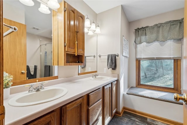 bathroom featuring double vanity, visible vents, a stall shower, and a sink