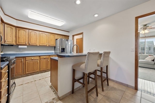 kitchen featuring dark countertops, a kitchen breakfast bar, stainless steel appliances, and light tile patterned flooring