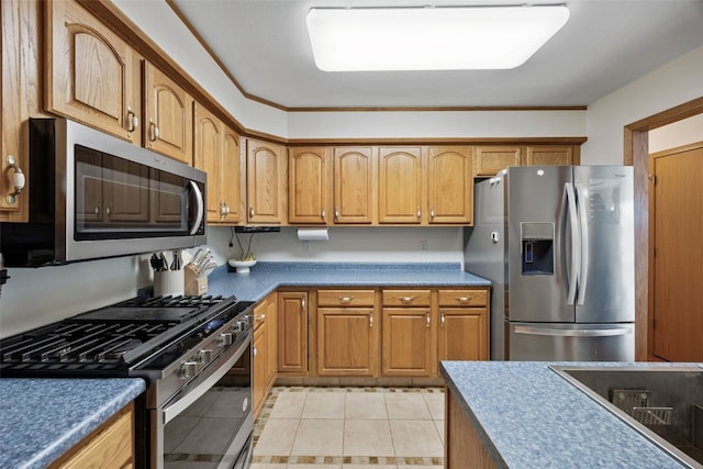 kitchen featuring light tile patterned flooring, brown cabinets, and appliances with stainless steel finishes