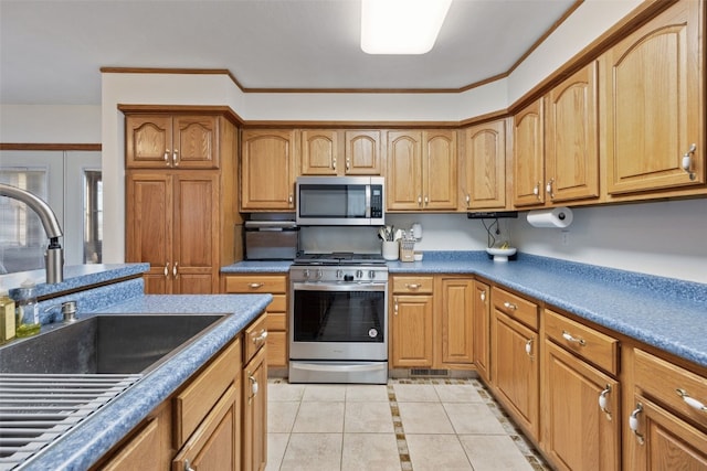 kitchen featuring dark countertops, brown cabinets, light tile patterned flooring, stainless steel appliances, and a sink