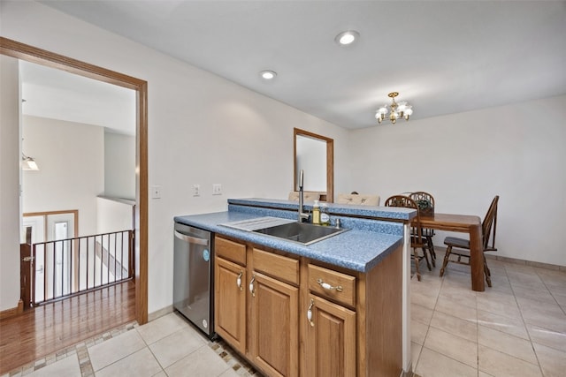 kitchen featuring dark countertops, a sink, light tile patterned floors, a notable chandelier, and stainless steel dishwasher