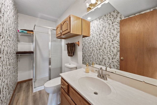 bathroom with wallpapered walls, toilet, wood finished floors, and a stall shower