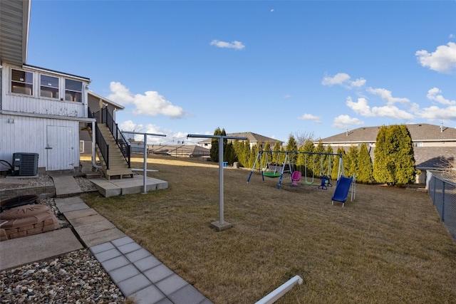 view of play area with stairway, cooling unit, a fenced backyard, and a lawn