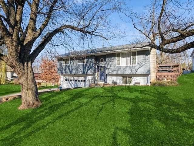 raised ranch with a garage, a wooden deck, a front lawn, and entry steps