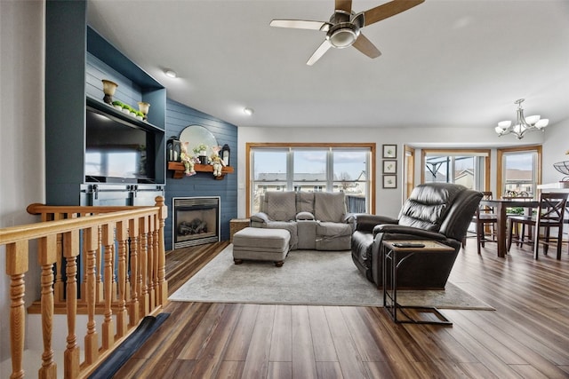 living area with ceiling fan with notable chandelier, wood finished floors, and a large fireplace