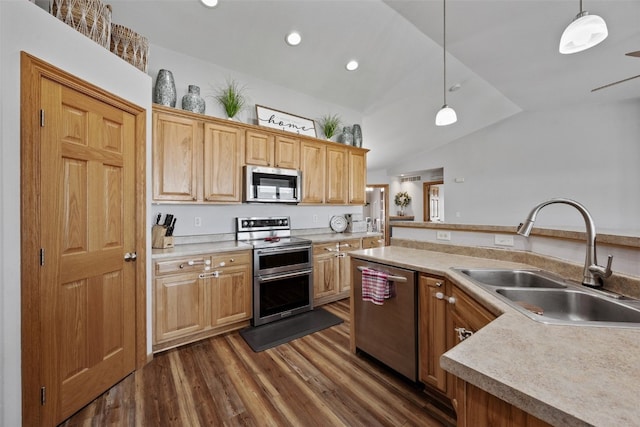 kitchen with a sink, dark wood-style floors, appliances with stainless steel finishes, light countertops, and vaulted ceiling