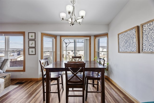 dining area with a wealth of natural light, light wood-style flooring, and a chandelier