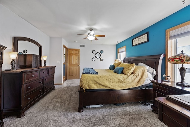 bedroom featuring visible vents, multiple windows, carpet floors, and ceiling fan