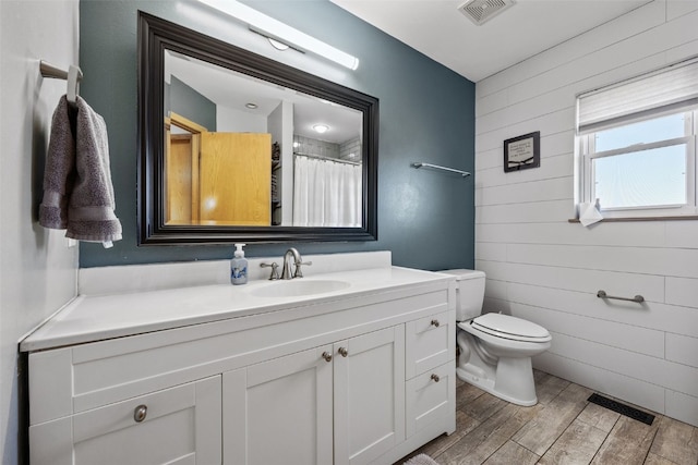 bathroom featuring vanity, toilet, wood finished floors, and visible vents