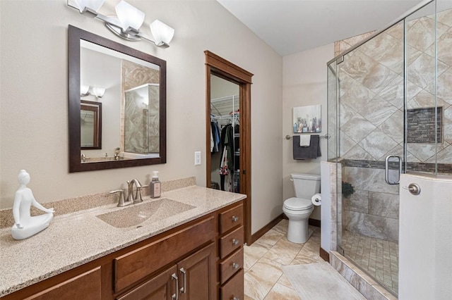 bathroom featuring vanity, a shower stall, a spacious closet, and toilet