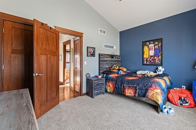 carpeted bedroom with visible vents and high vaulted ceiling