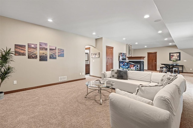 living room with visible vents, recessed lighting, arched walkways, baseboards, and light colored carpet